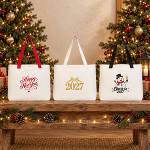 Three New Year 2027 canvas tote bags, 18 x 14 x 3 inches, with red, beige and black knitted straps standing on a rustic wooden bench with Happy New Year, gold 2027 and snowman prints