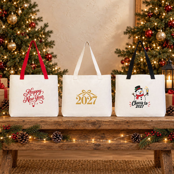 Three New Year 2027 canvas tote bags, 18 x 14 x 3 inches, with red, beige and black knitted straps standing on a rustic wooden bench with Happy New Year, gold 2027 and snowman prints