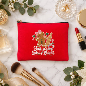 Red clutch makeup bag with a Baking Spirits Bright gingerbread print on a marble vanity with perfume, lipstick, makeup brushes and gold ornaments