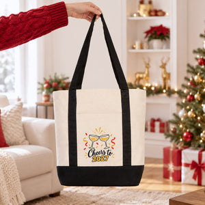 Hand lifting a black strap canvas tote bag with a Cheers to 2027 champagne print in a bright Christmas living room