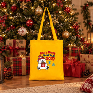Golden yellow cotton tote bag with a Beary Happy New Year 2027 polar bear print standing under a Christmas tree among wrapped gifts