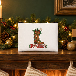 White clutch bag with a Howdy Holidays cowboy boot print standing on a Christmas fireplace mantel with a garland, candles and stockings
