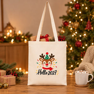 Natural cotton gabardine tote bag with a reindeer Hello 2027 print filled with Christmas gifts on a wooden table