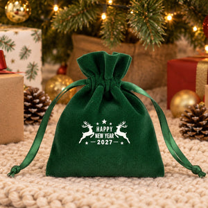 Green velvet drawstring pouch printed with a Happy New Year 2027 leaping reindeer design on a cream knit tree skirt among wrapped presents under the Christmas tree