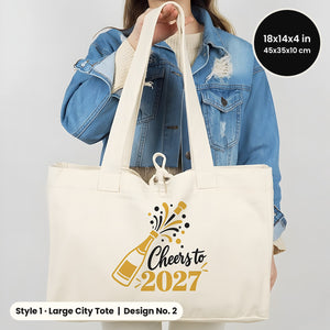 Natural Large City canvas tote bag held by hand printed Cheers to 2027 with a gold champagne bottle