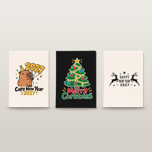Studio photo of three canvas notebooks with Capy New Year 2027, Merry Christmas tree and Happy New Year 2027 reindeer prints