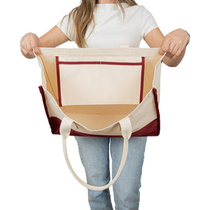 Real photo of a model holding the burgundy canvas tote open, showing the roomy inside and the inner pocket
