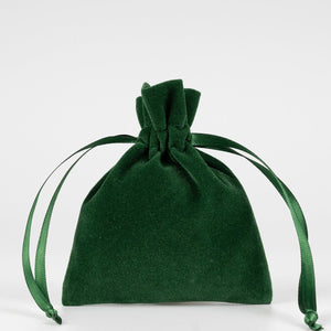 Real photo of a plain green velvet drawstring pouch standing upright with its satin ribbon ends knotted