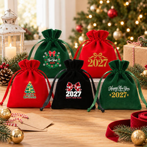 Five red, green and black velvet drawstring pouches with different Christmas and New Year 2027 designs arranged as bulk party favours and gifts for guests, a team or a class