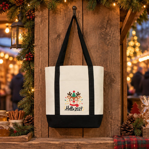 Black strap canvas tote bag with a reindeer Hello 2027 print hanging at a Christmas market stall as a reusable shopping bag