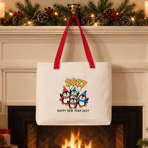 Large canvas tote bag with red knitted straps and a party penguins 2027 print hanging from a Christmas fireplace mantel as a gift stocking