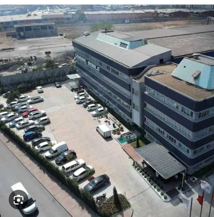 Aerial view of a large industrial building with a parking lot in front.