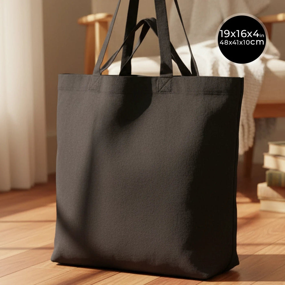 Black tote bag on a wooden floor with dimensions displayed