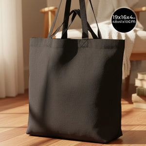 Black tote bag on a wooden floor with dimensions displayed