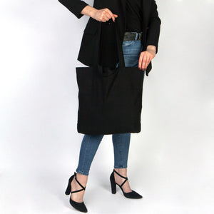Person holding a black tote bag against a white background