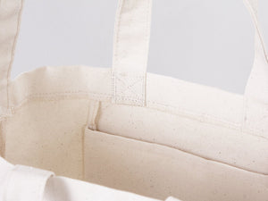 Close-up of a beige fabric bag with straps on a light gray background
