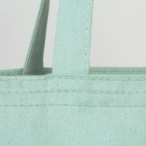 Close-up of a light blue tote bag with handles on a light gray background