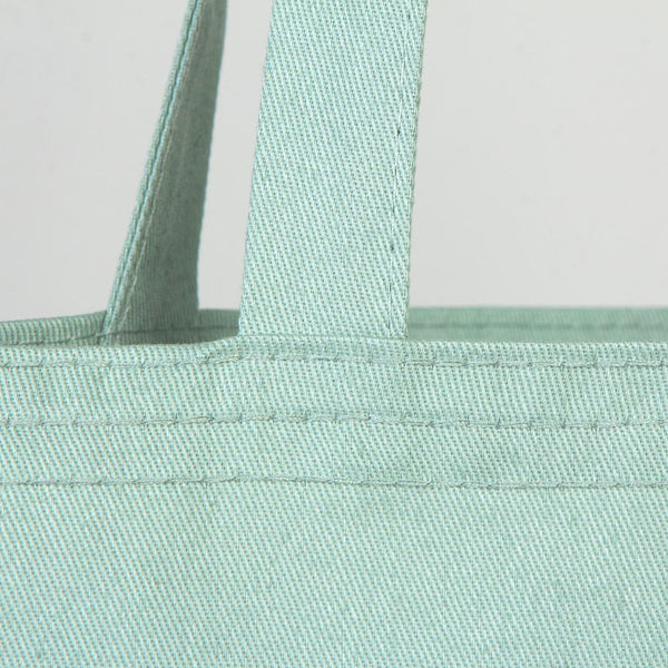 Close-up of a light blue tote bag with handles on a light gray background