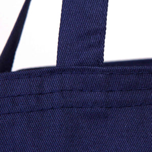 Close-up of a navy blue tote bag with handle and stitching details.