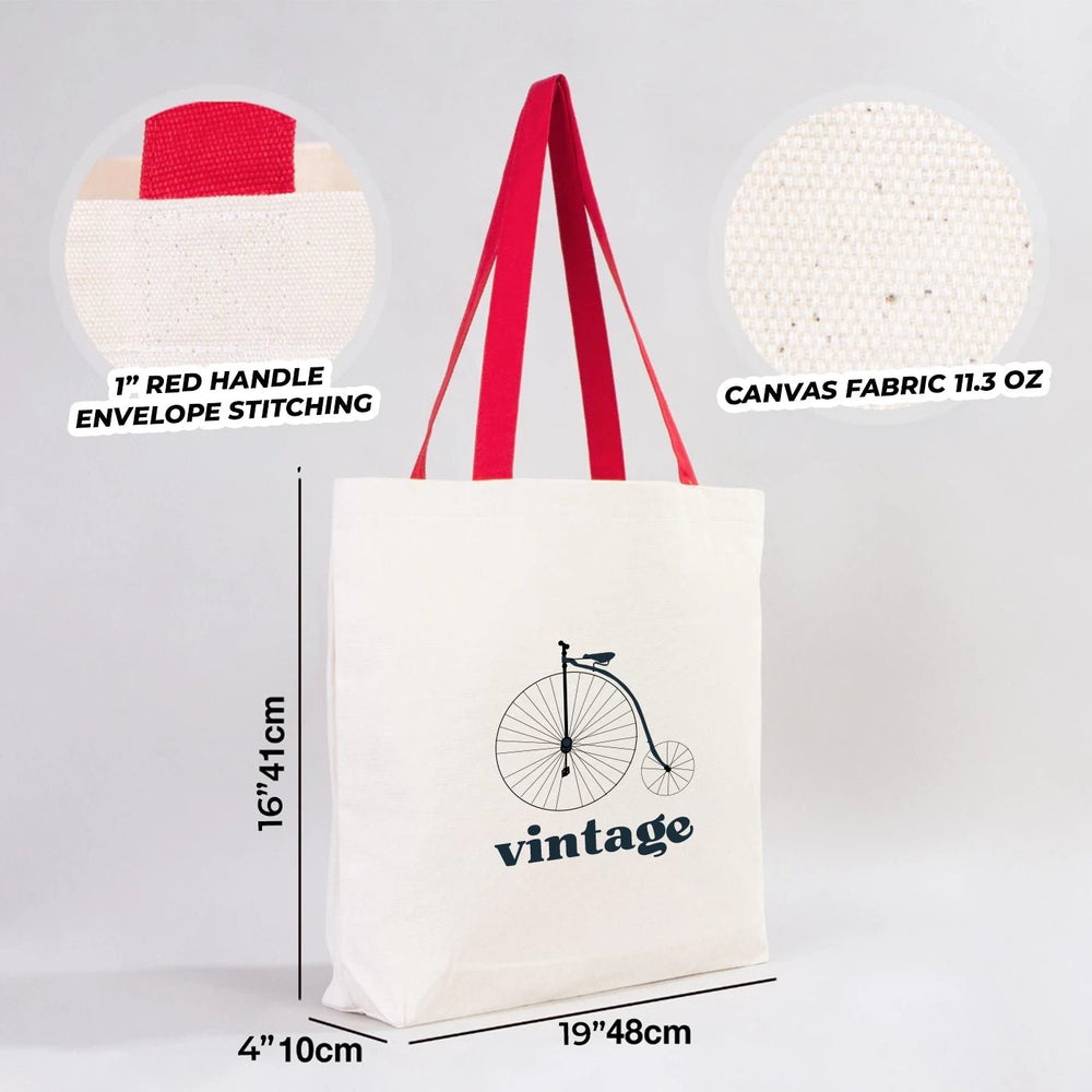 Beige tote bag with red handles and customizable text area on a wooden surface.