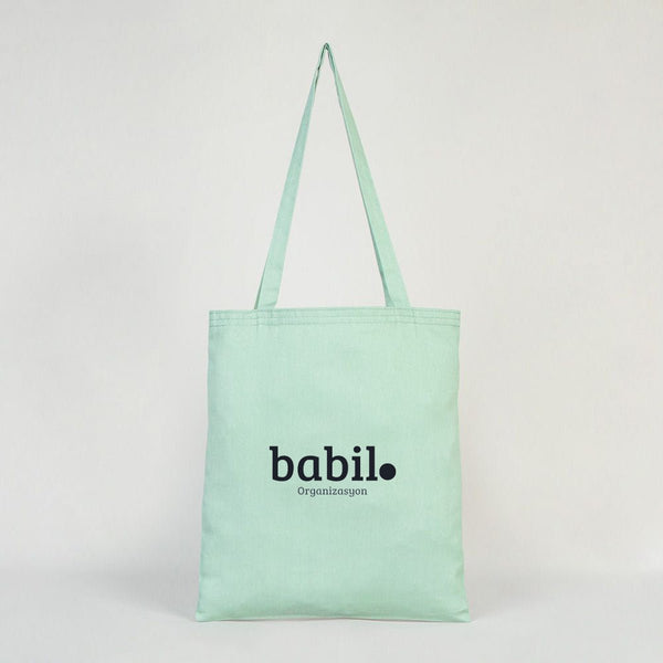 Mint green tote bag with 'babil' branding on a light gray background