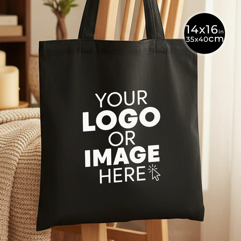 Black tote bag with customizable text 'YOUR LOGO OR IMAGE HERE' on a neutral background