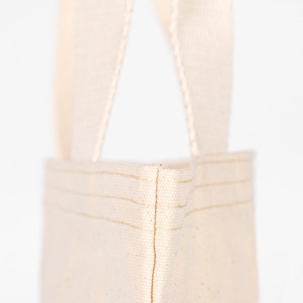 Close-up of a beige tote bag with handles on a white background