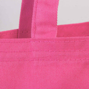 pink cotton tote bag close-up showing stitching and handle detail.
