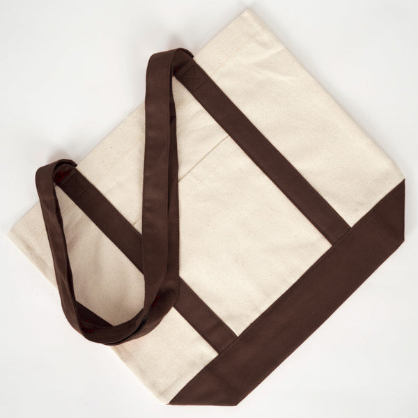 Plat neergelegde canvas tas met donkerbruine hengsels - Pamusan.nl