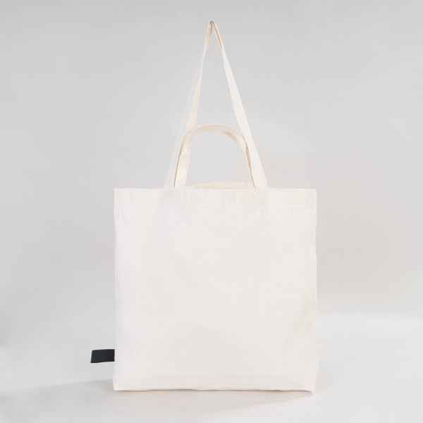 White tote bag with a black label on a light gray background