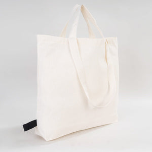 White tote bag with a black tag on a light gray background
