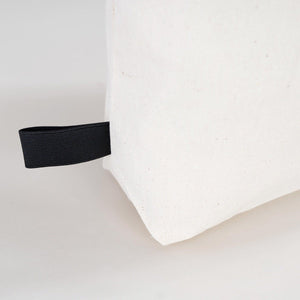 White pillow with a black elastic band on a light gray background