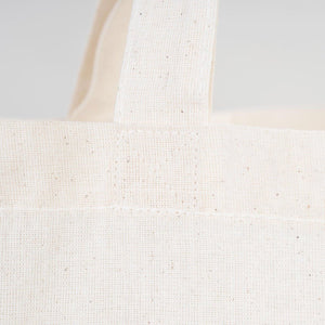 Close-up of a textured white tote bag on a light gray background