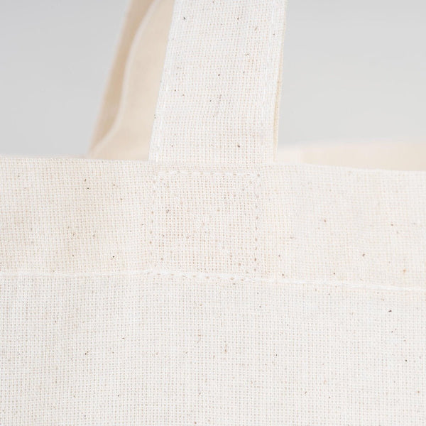 Close-up of a textured white tote bag on a light gray background