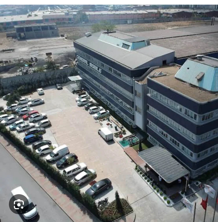 Aerial view of a large industrial building with a parking lot in front.