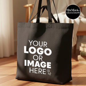 Black tote bag with customizable text on a wooden floor
