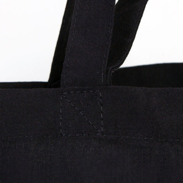 Close-up of a black tote bag with handles on a white background