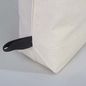 Close-up of a beige cushion with a black strap on a light gray background
