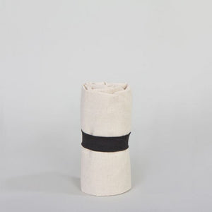 Rolled-up beige blanket with a black band on a light gray background
