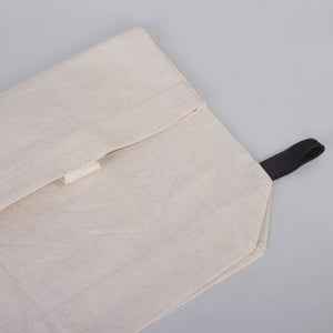Beige fabric pouch with a black strap on a gray background