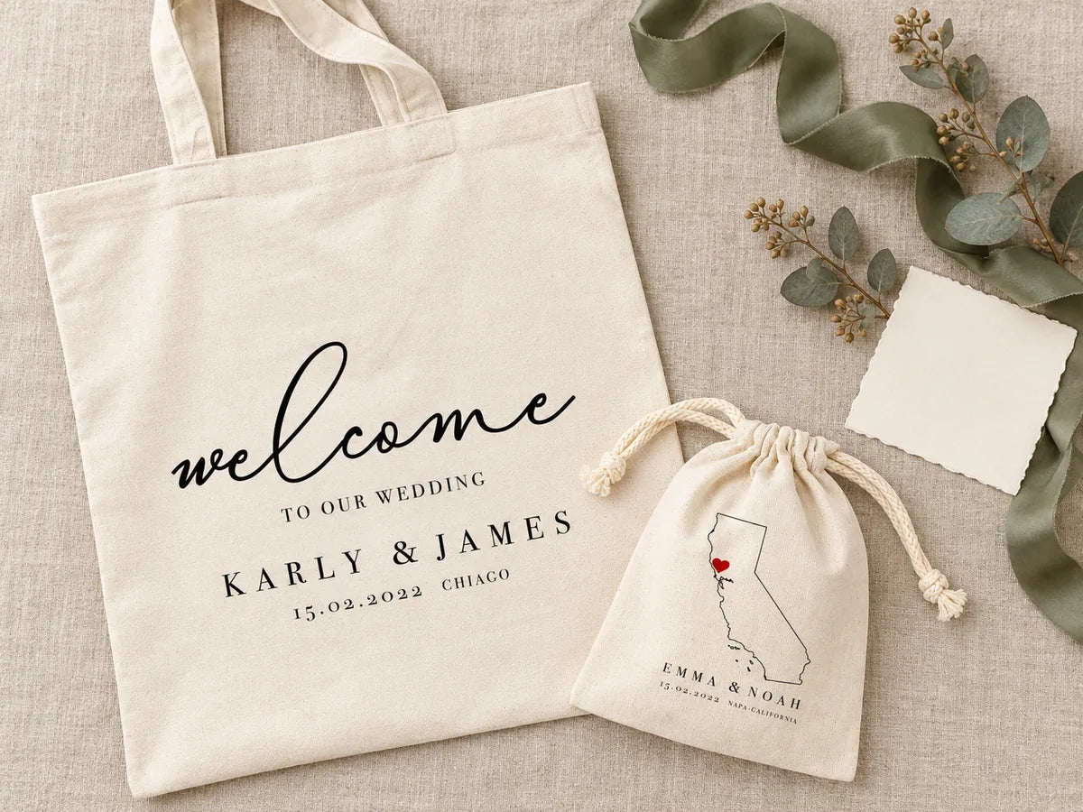 Flatlay van bovenaf op linnen: tas ‘Karly & James’ en trekkoordzakje met kaart van Californië, saliegroen zijden lint, gedroogde eucalyptus en een blanco ivoorkleurige kaart
