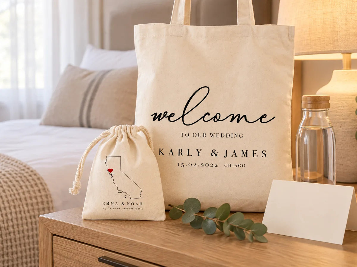 Hotelkamer met eiken nachtkastje en warme lamp: welkomsttas ‘Karly & James’ rechtop, ervoor een trekkoordzakje met kaart van Californië, een glazen waterfles, een blanco welkomstkaart en eucalyptus